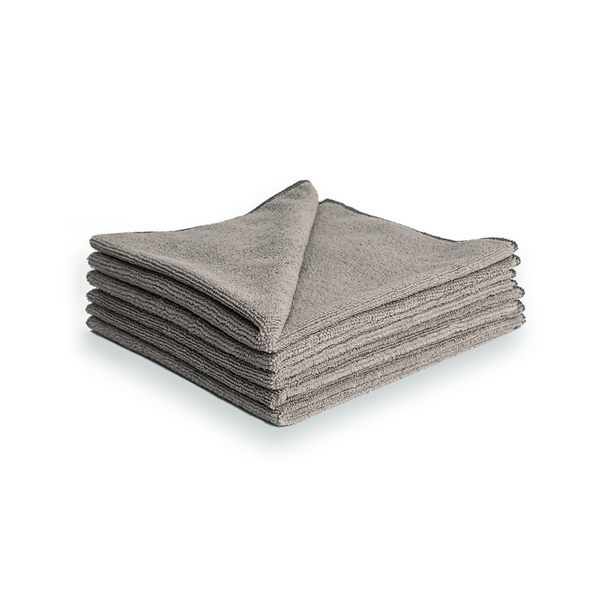 A stack of light grey microfibre cleaning cloths on a white background
