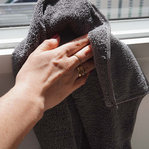A person using a grey microfibre cloth to clean a window