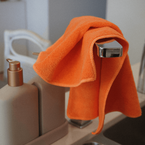 A orange microfibre cloth on a kitchen tap