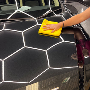 Yellow microfibre cloth wiping hood of black car