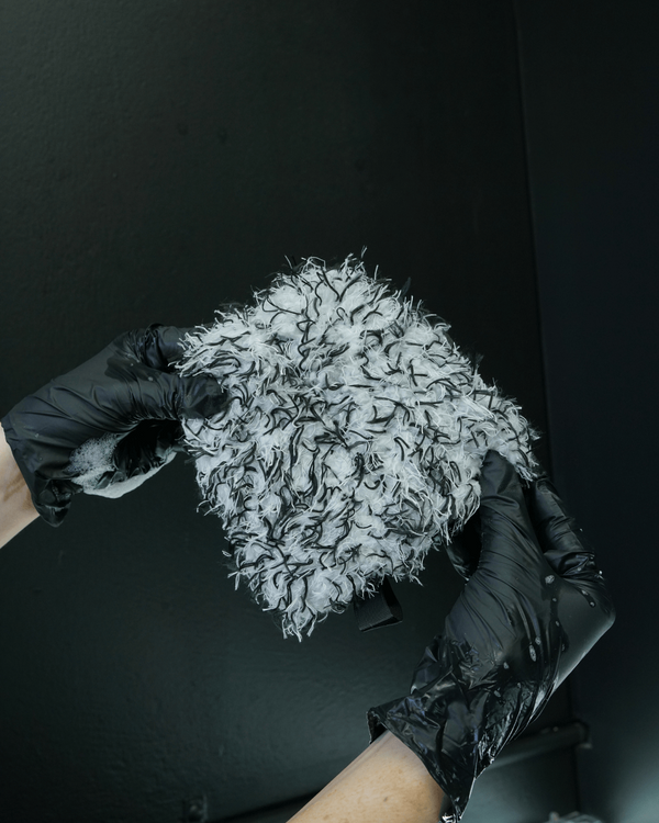 A person wearing black gloves holding a black and white wheel mitt