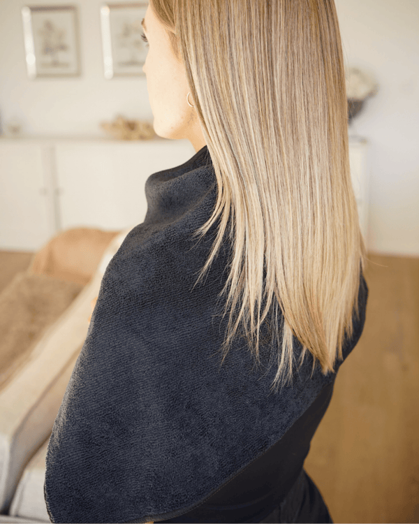 A woman with a black hairdressing towel over her back