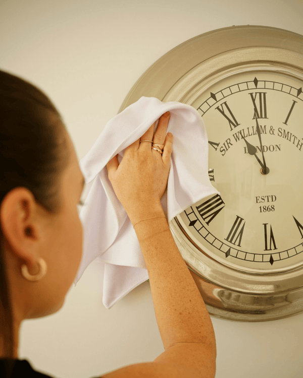 Person cleaning a vintage clock with a microfibre glass cloth
