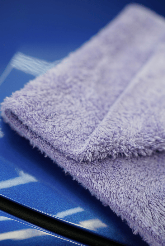 A folded purple microfibre cloth on a blue surface