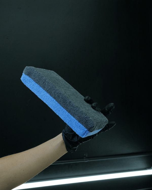 A person wearing black gloves holding a extra large no soak ceramic applicator