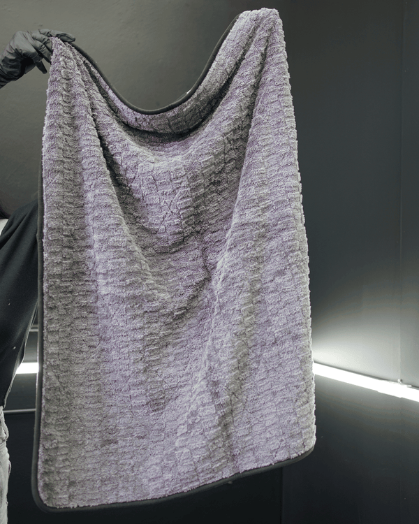 a person holding up a large grey car drying microfibre towel