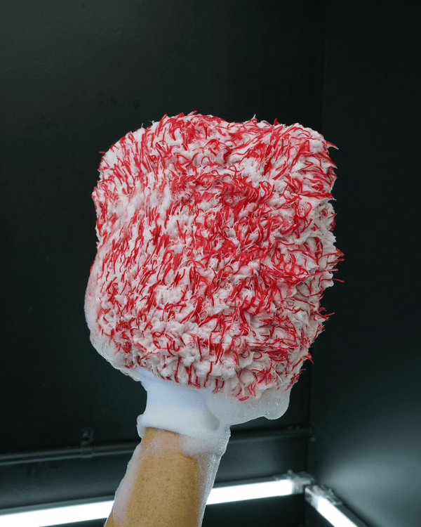 A person using a red an white microfibre wash mitt