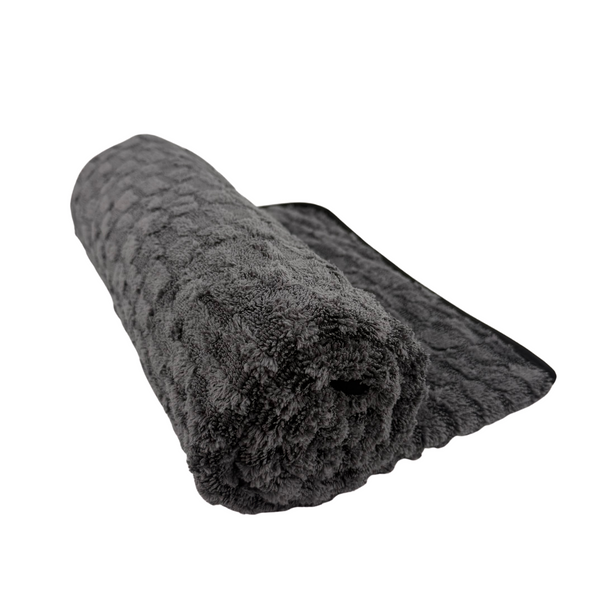 Dark grey microfibre drying towel rolled up on a white background