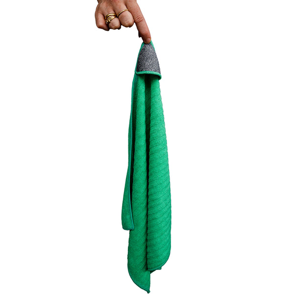 A person holding a green cloth with a scrub corner on a white background