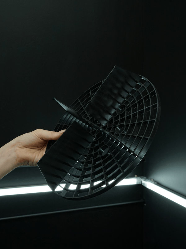Hand holding a black grit guard against a dark background