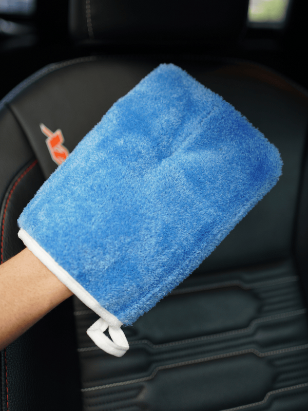 Blue microfiber cleaning mitt held by a person in a car interior.