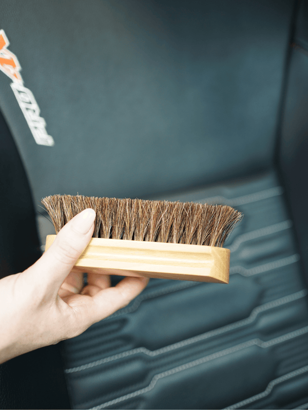 Hand holding a horsehair brush against a blurred background