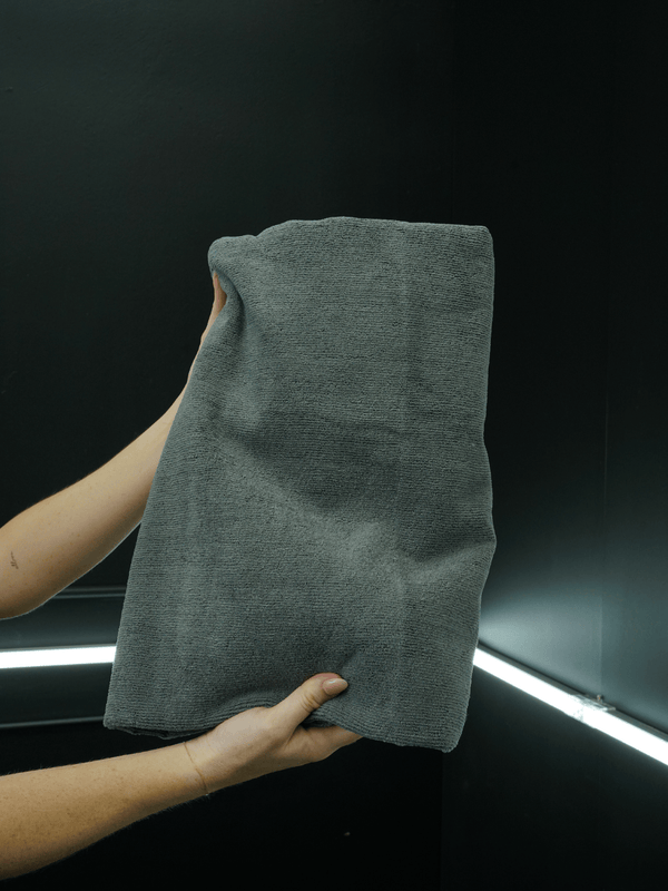 Person holding a large grey towel in a dark background