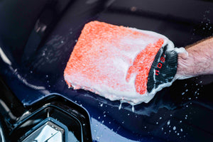 Close-up of Orange Microfibre Wash Mitt with ADBL Shampoo Foam on Dark Blue Car Paint - Safe Hand Wash Detailing