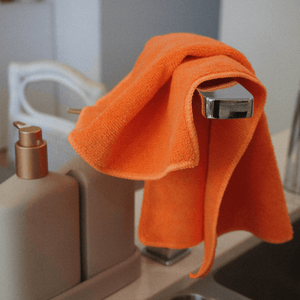 A orange microfibre cloth on a kitchen tap
