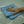 Hand with a ring holding a blue microfibre cloth on a white surface