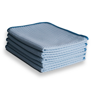 A stack of light blue waffle weave microfibre cloths with a dark blue border on a white background 