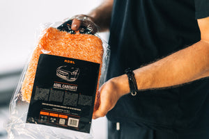 A person opening a packet with a orange microfibre wash mitt in it