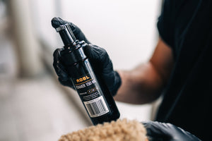 Hand in black glove dispensing foam product from ADBL FOAMER 150 ML pump bottle onto cleaning mitt