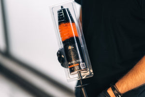 Person in black gloves holding ADBL Wheel Dagger brush in retail blister packaging