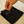 Hand holding a black towel with a brand label on a light surface