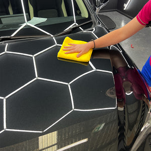 A Yellow microfibre cloth being used by a person on the bonnet of a car 