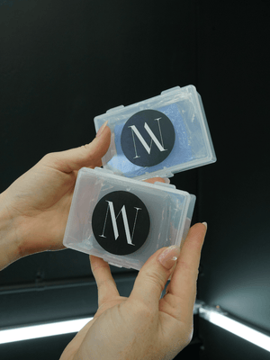 Hand holding two transparent containers with a logo on a dark background