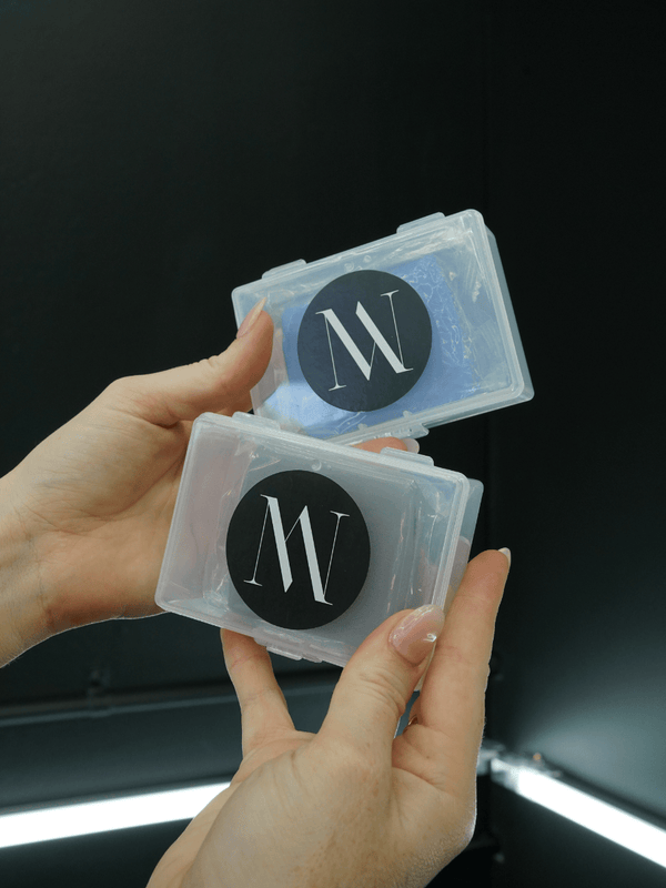 Hand holding two transparent containers with a logo on a dark background