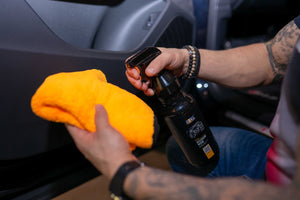 Person spraying ADBL INTERIOR WOW onto an orange microfibre towel for interior dressing