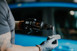Person in black glove applying ADBL Black Outer exterior dressing onto a foam applicator pad