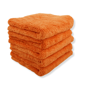 A stack of orange plush microfibre cloths on a white background