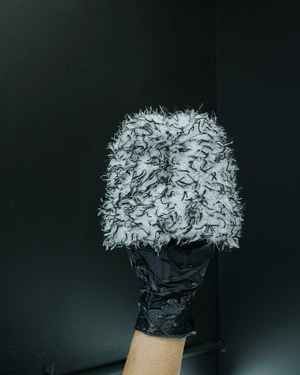 A person wearing black gloves holding a black and white wheel cleaning mitt