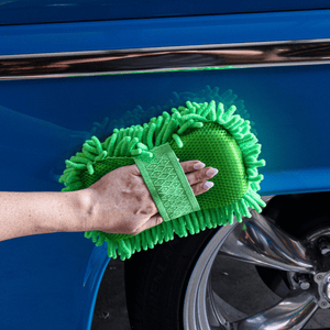 Person cleaning a blue car with a green noodle sponge