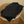 Black towel folded on top a wicker laundry basket against a neutral wall.