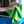 Person cleaning a blue vehicle with a green microfibre buffing cloth