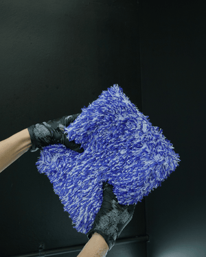 A person wearing black gloves holding a large microfibre car wash mitt