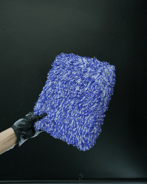 A person wearing black gloves holding a large microfibre car wash mitt