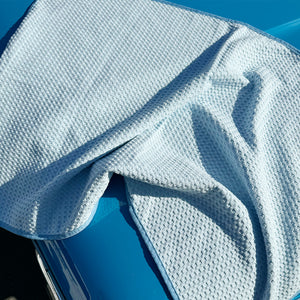 A light blue waffle weave drying towel spread over a car bonnet