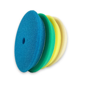 A stack of four buffing pads in blue, green, yellow, and white, designed for car detailing.