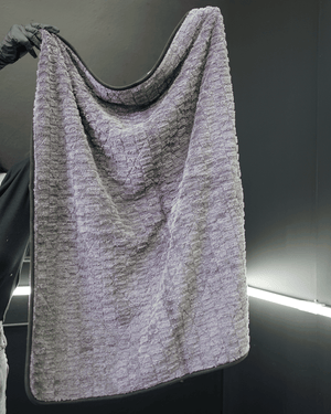 a person holding up a large grey car drying microfibre towel