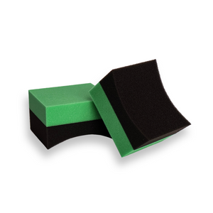 A pair of foam tyre dressing applicators, one green and one black, with a contoured design.