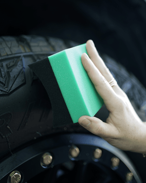 A person using a foam curved tyre dressing applicator