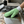 A green all-purpose microfibre cleaning mitt being used to clean a dirty stainless steel stove top