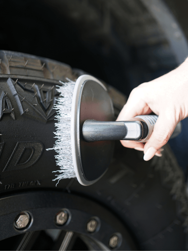 Person cleaning a car tire with a brush