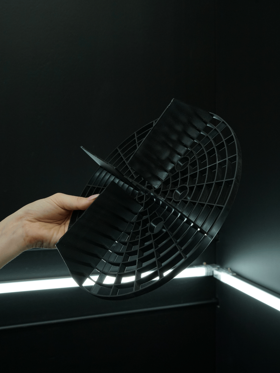 Hand holding a black grit guard against a dark background