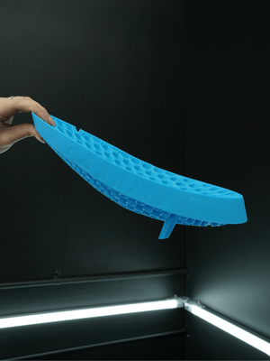 Blue curved grit guard held against a dark background