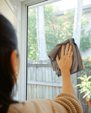 A person cleaning a window with a Korean microfibre glass cloth