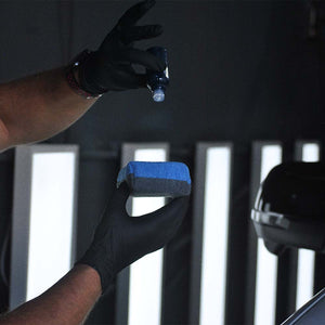 a large ceramic coating applicator being held by a person with ceramic coating being applied to the applicator 
