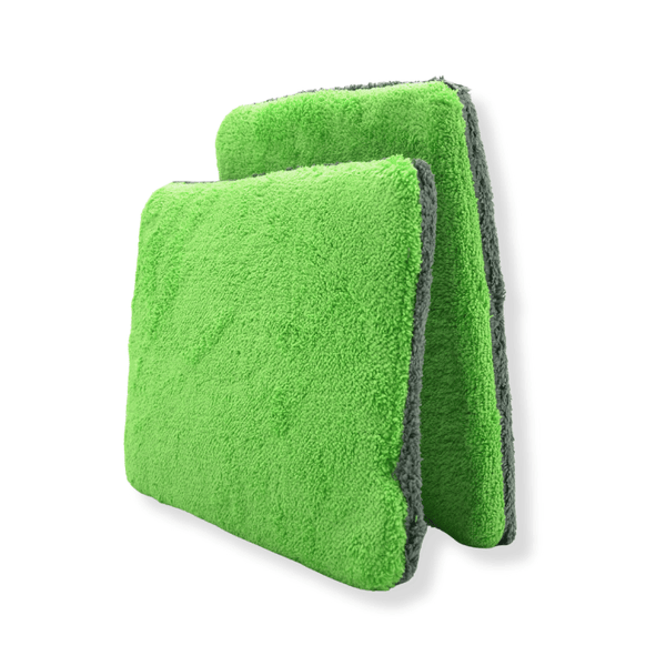 Two green and grey thin car wash pads on a white background