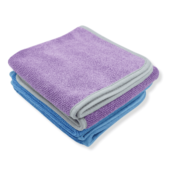 A stack of blue and purple microfibre drying towels on a white background 